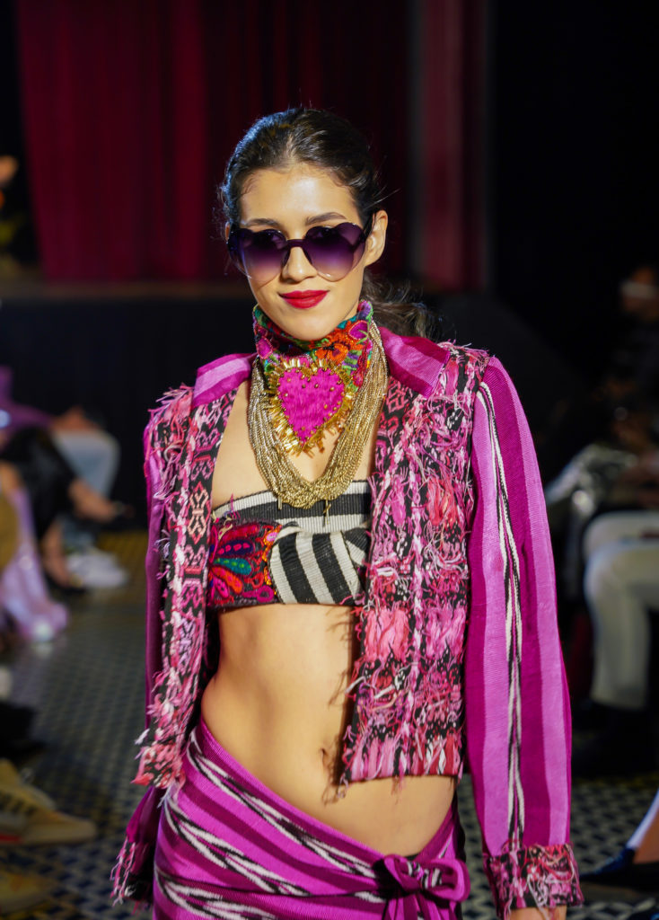 Pink woven jacket and skirt with heart shaped purple sunglasses,  Fashion show in Guatemala March 2023, textile design from latin American designers